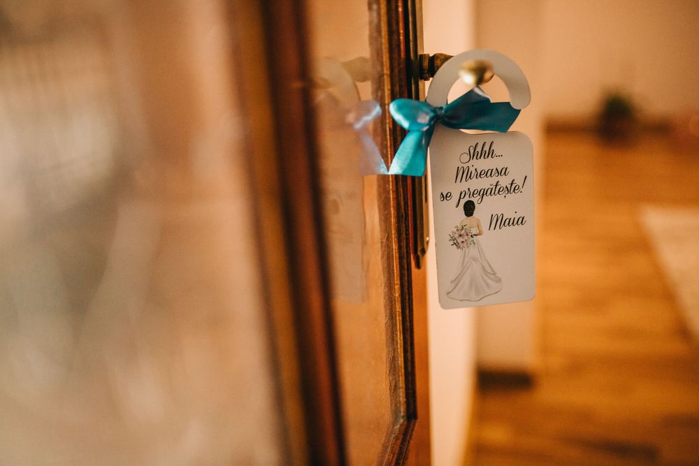 Wedding door hanger with teal ribbon bow and bride illustration on wooden door frame.