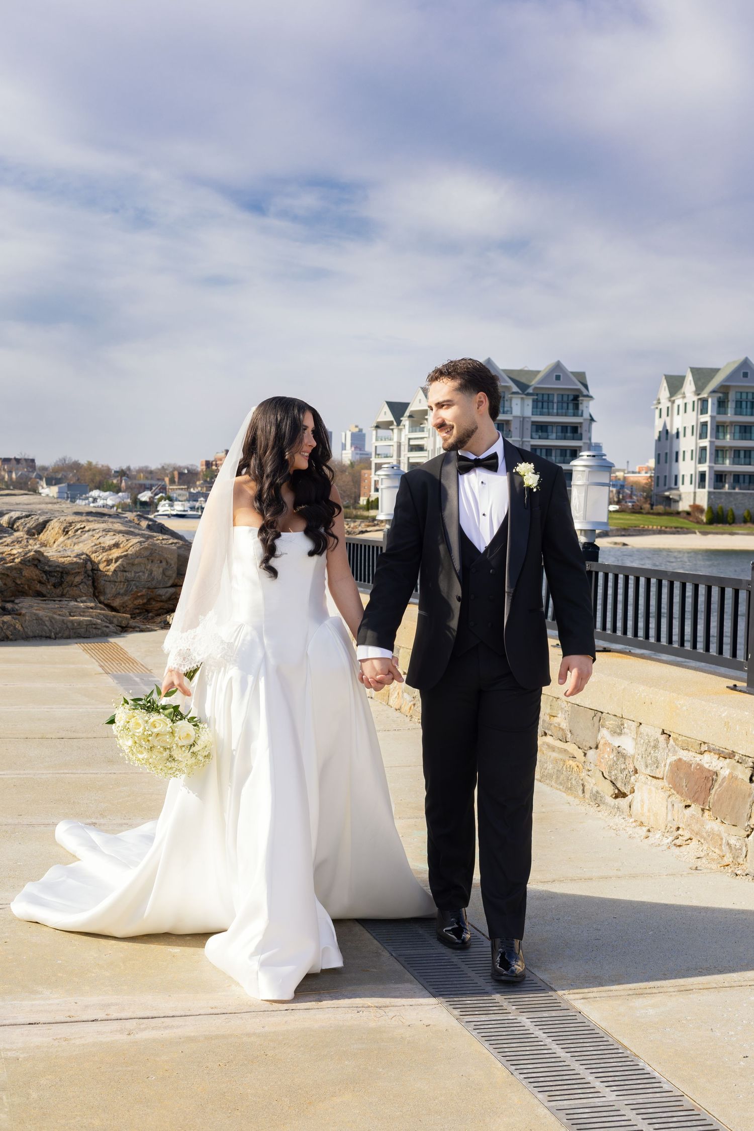 Bride and groom walking along the waterfront during their Glen Island Harbour Club wedding.