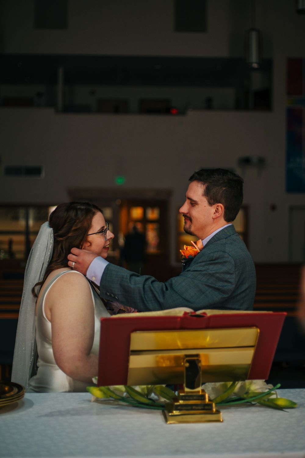 Bride and groom share a tender moment at the altar during their church wedding ceremony, exchanging loving glances.