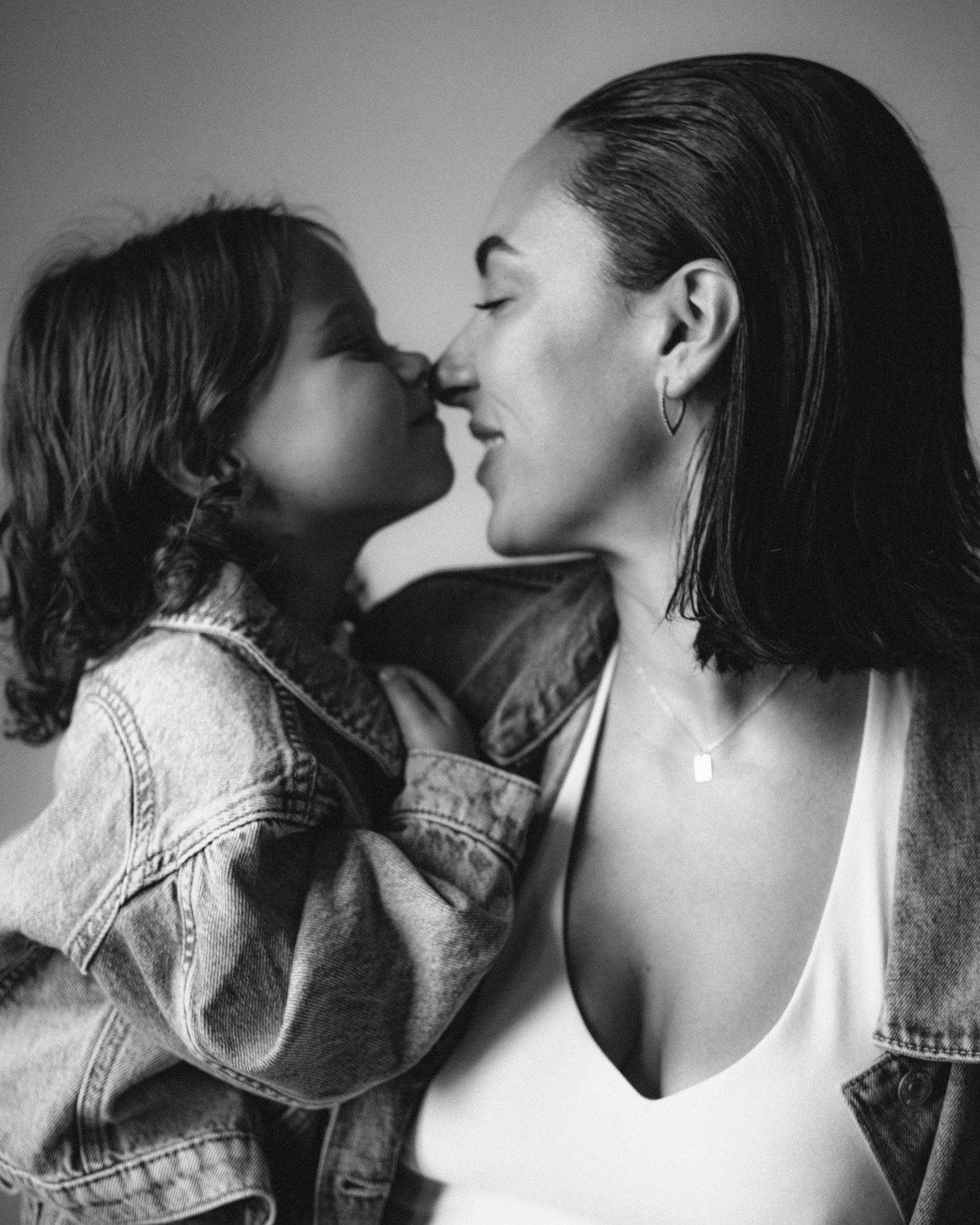Black and white photo of a mother and young child sharing a tender nose-to-nose moment, both smiling softly.