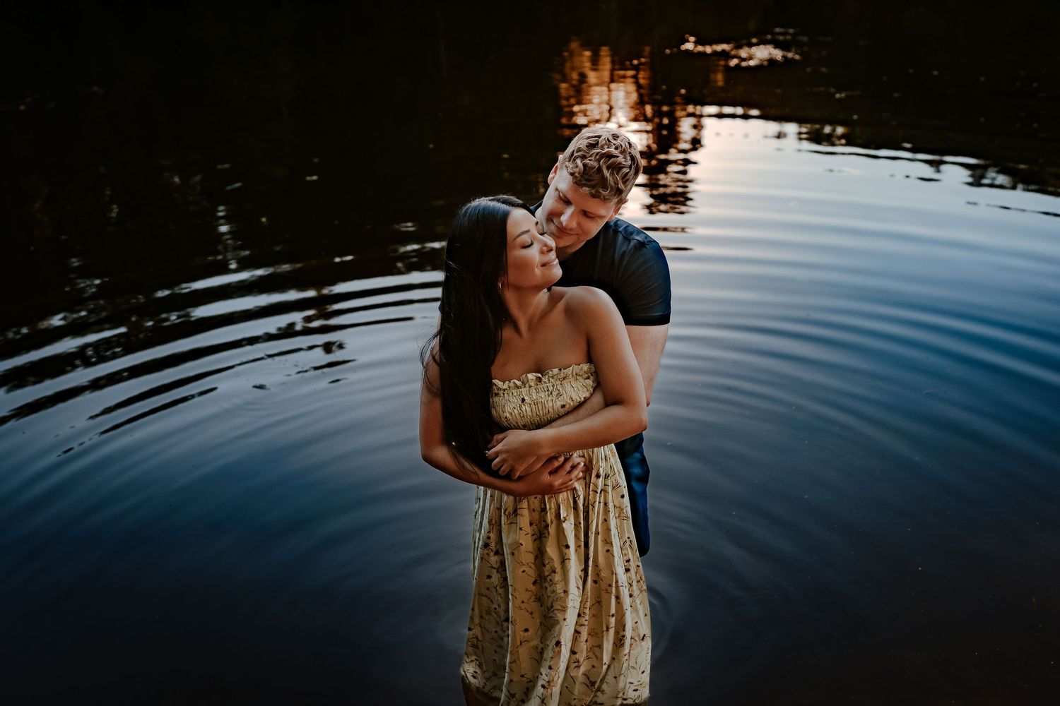 An intimate sunset moment shared while standing in reflective water.