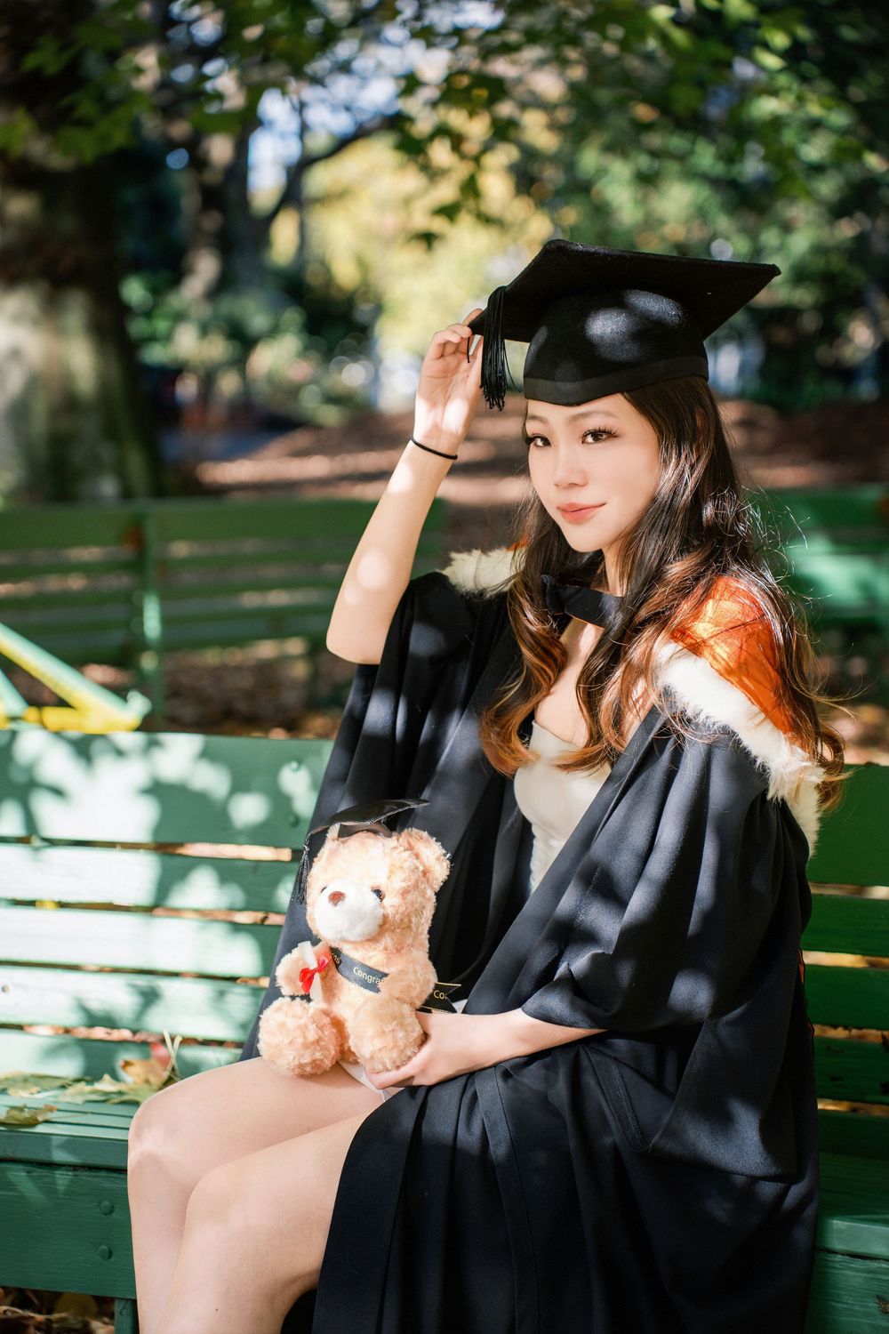 A portrait of a graduate student sitting on a park bench in Auckland.