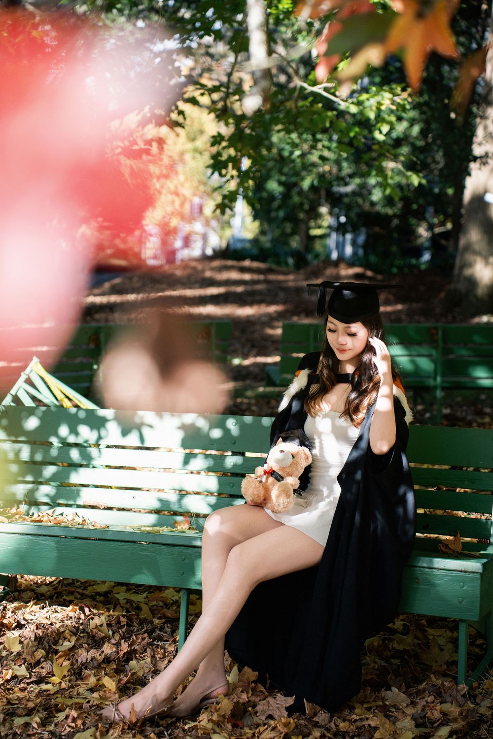 A student in academic regalia relaxing on a park bench in Auckland.