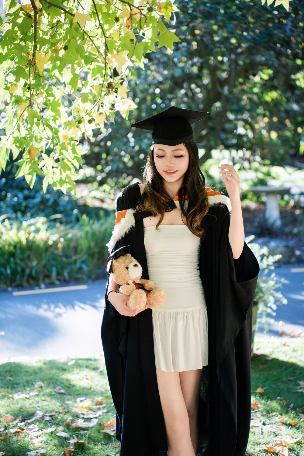 A graduate posing in a sunlit garden during an Auckland graduation photography session.