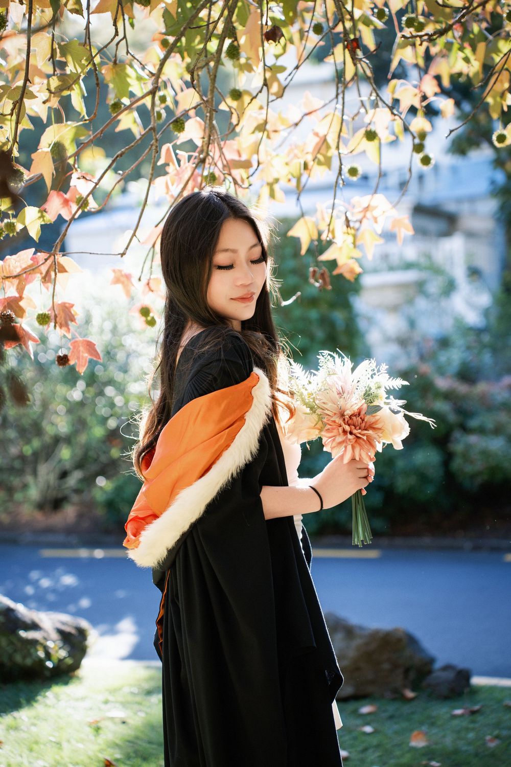 A graduate student posing with flowers in an Auckland outdoor garden.