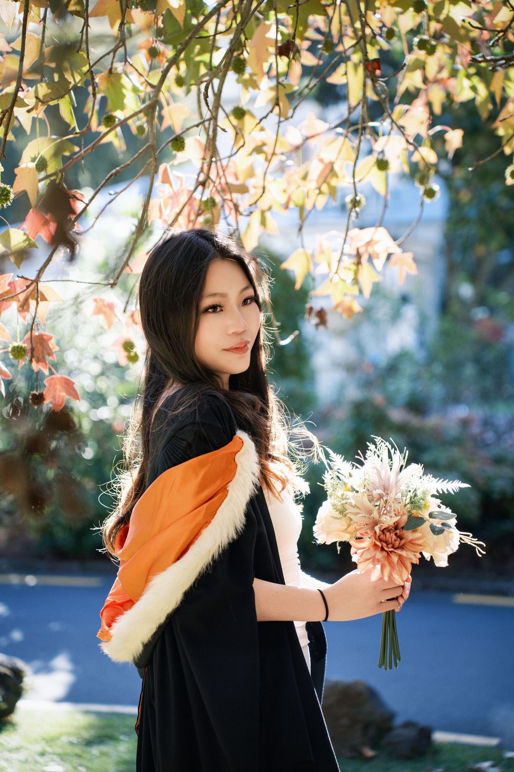 Close-up portrait of a graduate with flowers during an Auckland graduation photography session.