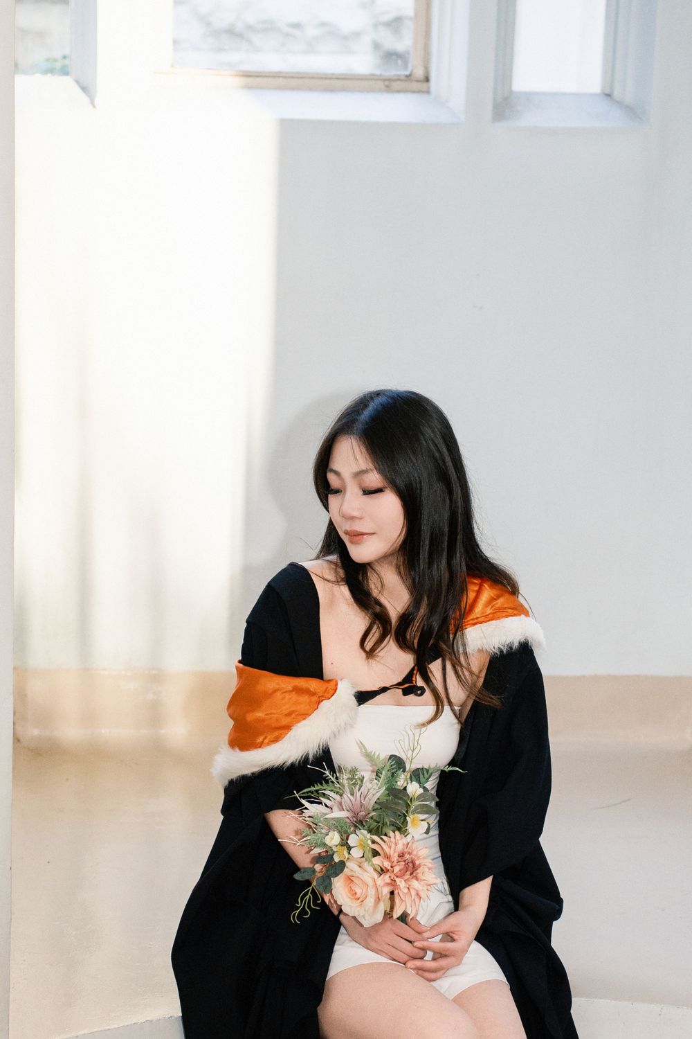 A soft-lit portrait of a graduate in academic regalia during an Auckland graduation photo session.