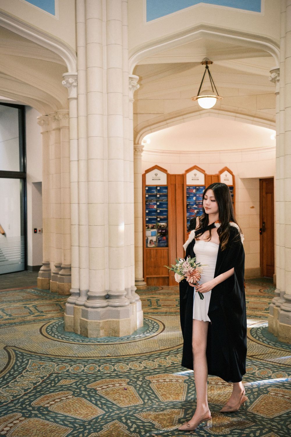 A graduate walking through a beautiful historic campus building in Auckland.