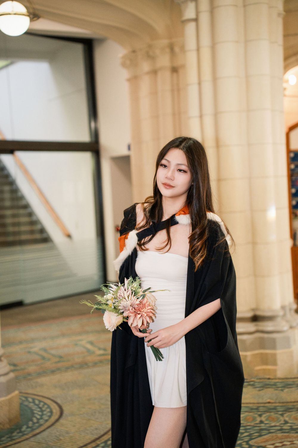 Elegant graduate posing inside a historic building for Auckland graduation photography.
