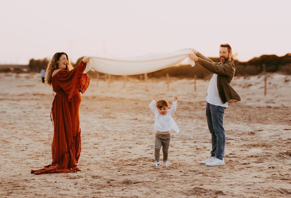Familia disfrutando de una sesión de fotos espontánea en la playa durante el atardecer en Girona.