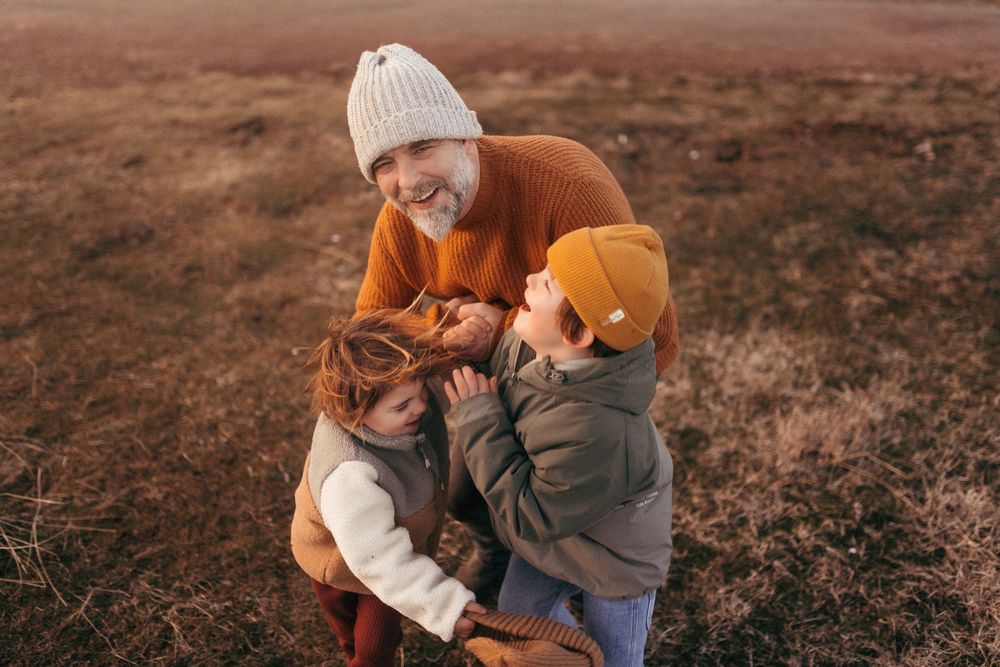 Padre abrazando a sus hijos durante una sesión de fotografía familiar al atardecer en Girona.