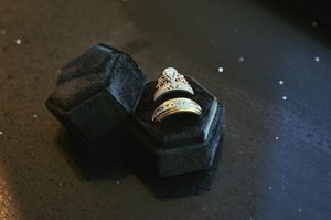 Diamond engagement ring and wedding band displayed in a black velvet ring box on a dark surface.