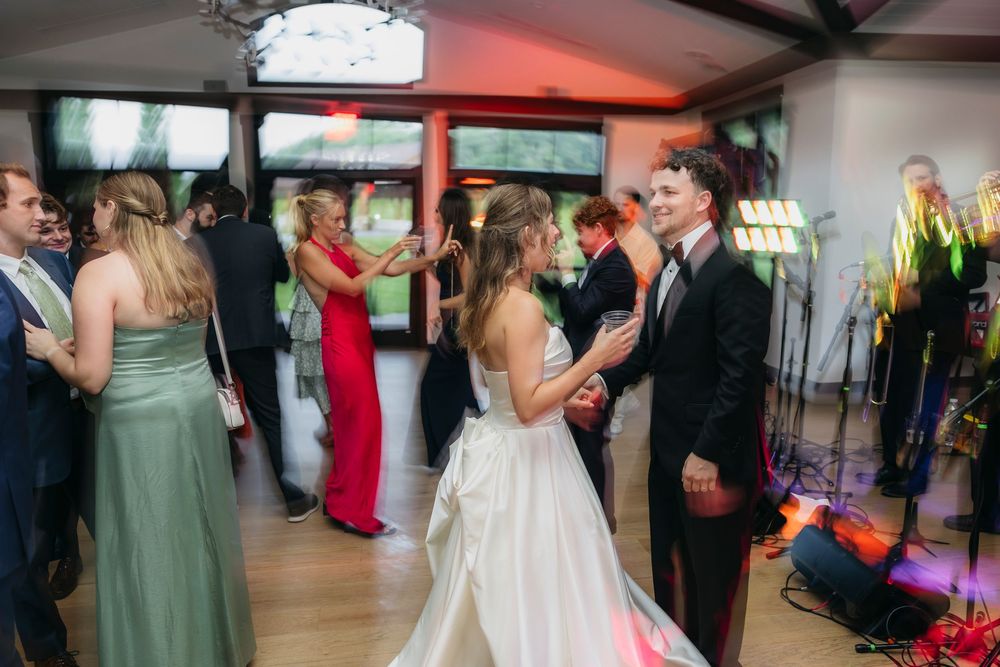 Bride and groom share a dance at elegant  Wisconsin wedding reception with guests in formal attire celebrating on the dance floor.