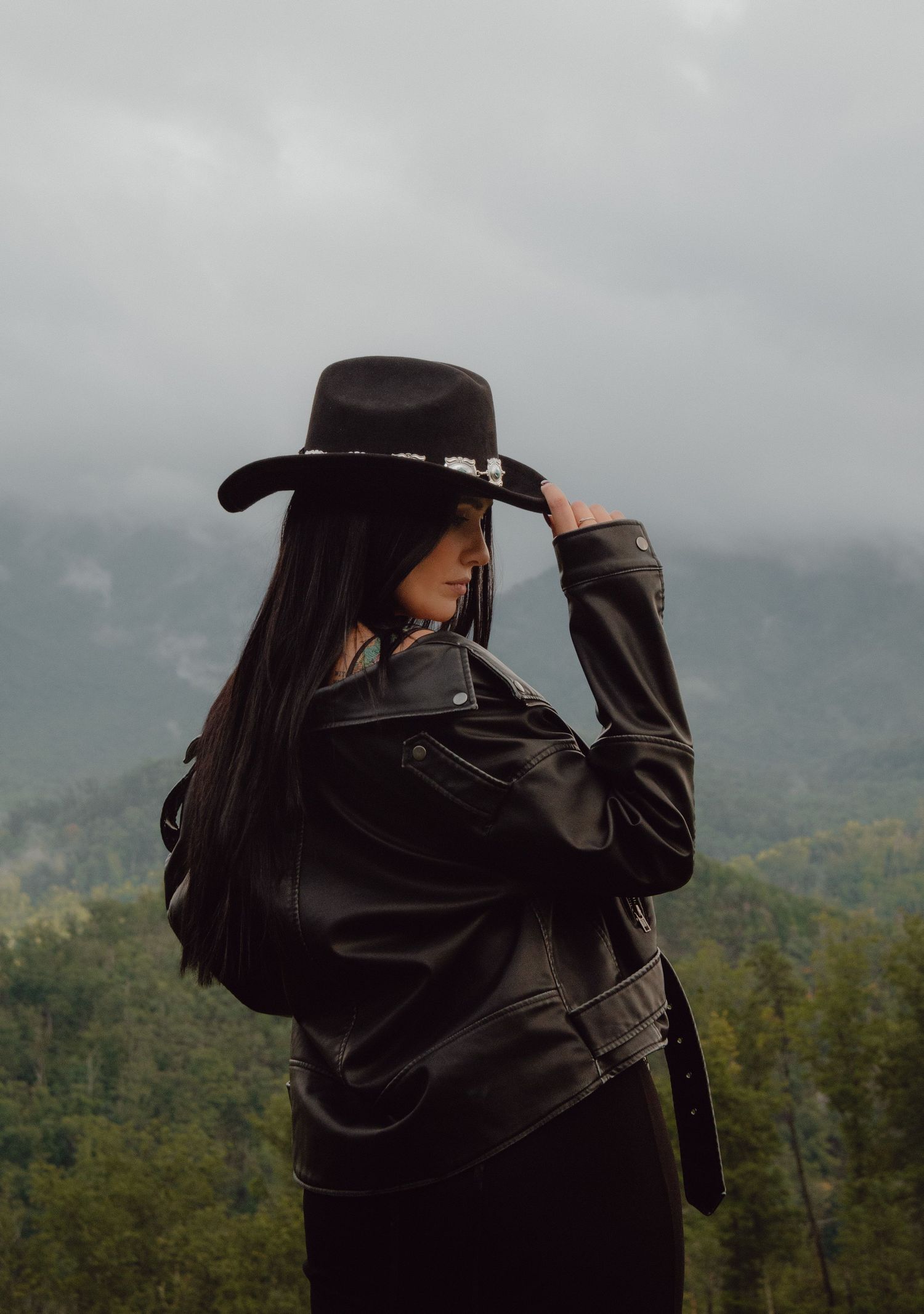 Model posing in front of the Smokey Mountains in Tennessee. Model is wearing a cowboy hat and leather jacket.