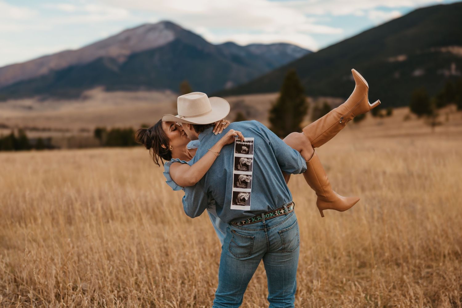 Cowboy dips wife while showing off ultrasound photos with their dog in the mountains of Red Lodge, Montana captured by Montana Photographer