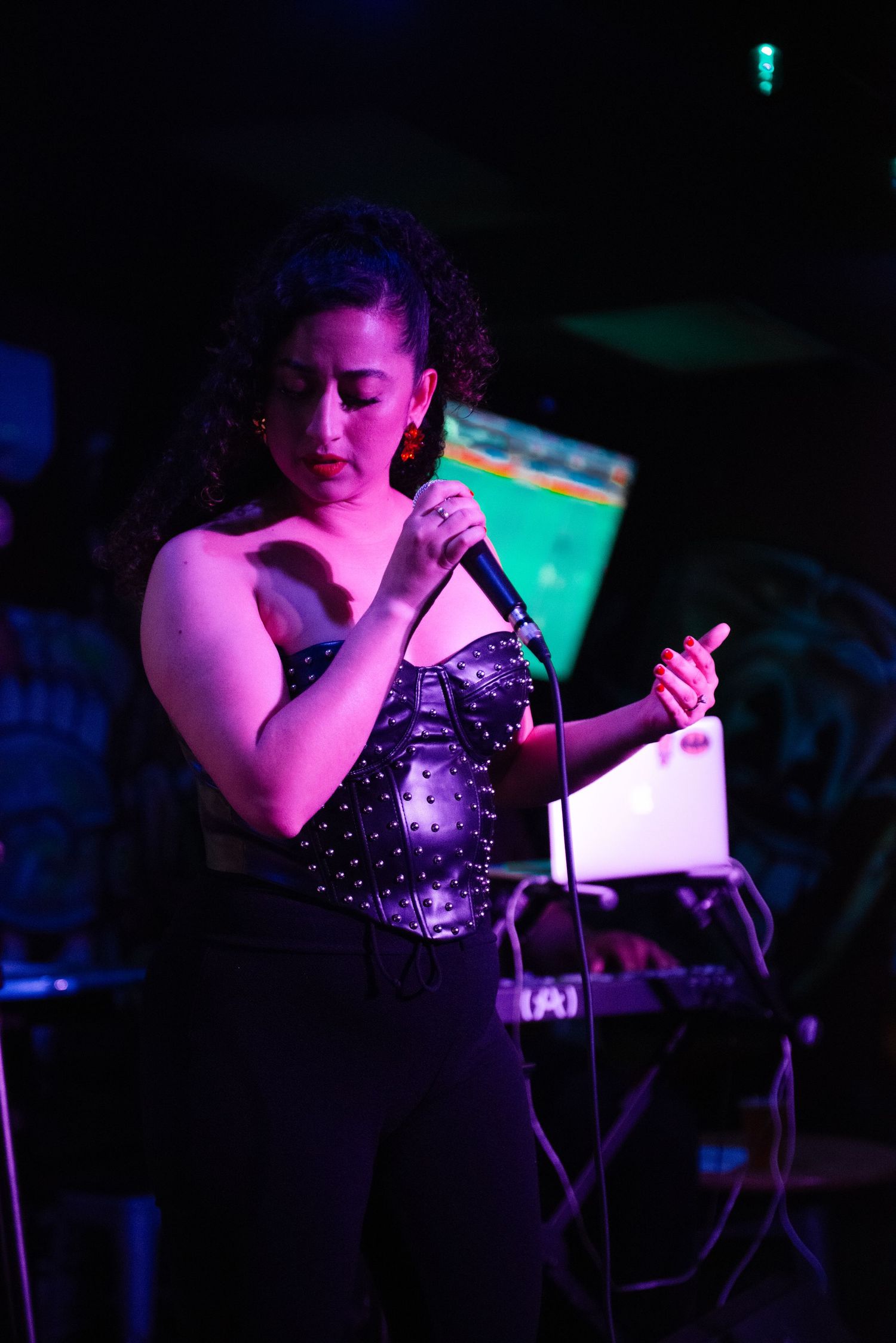 A singer performs on stage in a sparkly top under dramatic purple and blue lighting during a nightclub performance.