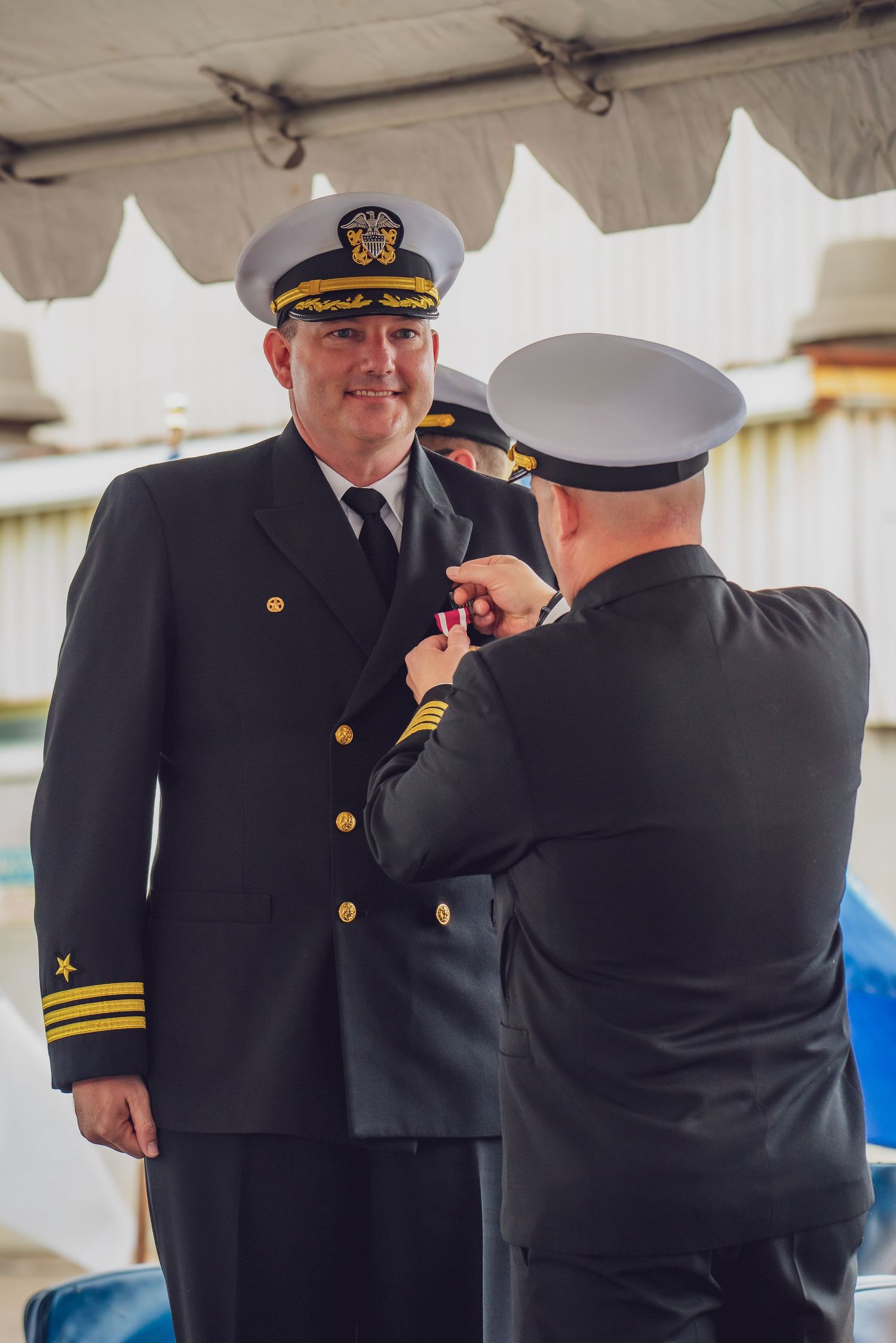 Military officers in dress uniforms stand together during a formal ceremony aboard a naval vessel.