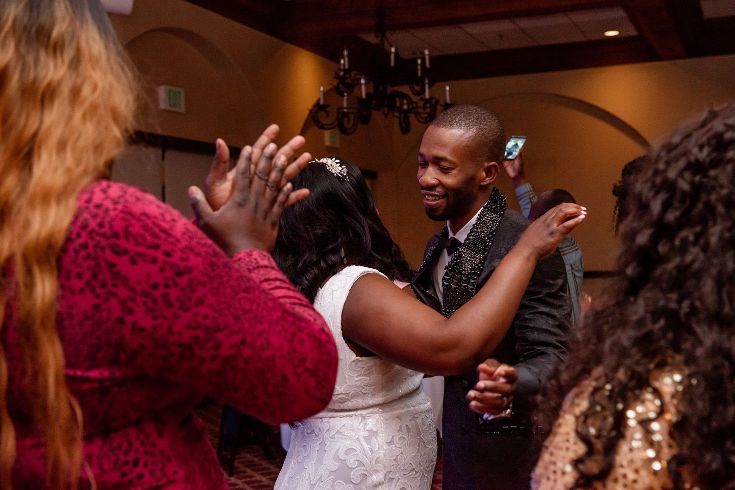 Couples dance together at a wedding reception in a dimly lit ballroom.