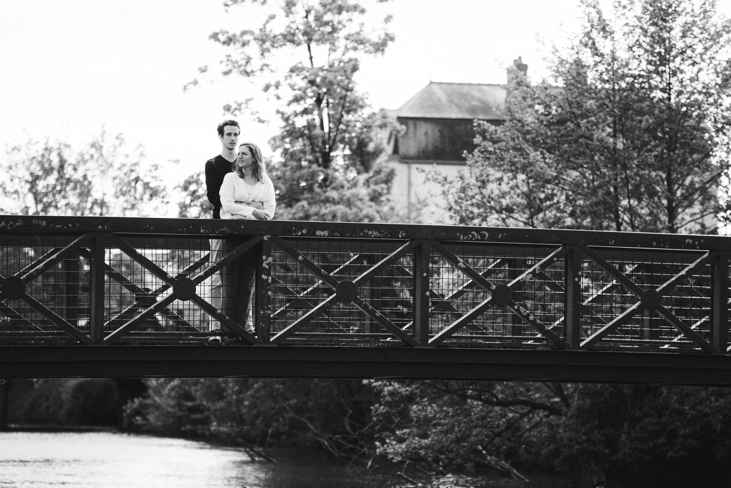 Couple photographié en noir et blanc sur un pont en bois en Bretagne, séance engagement romantique en extérieur.