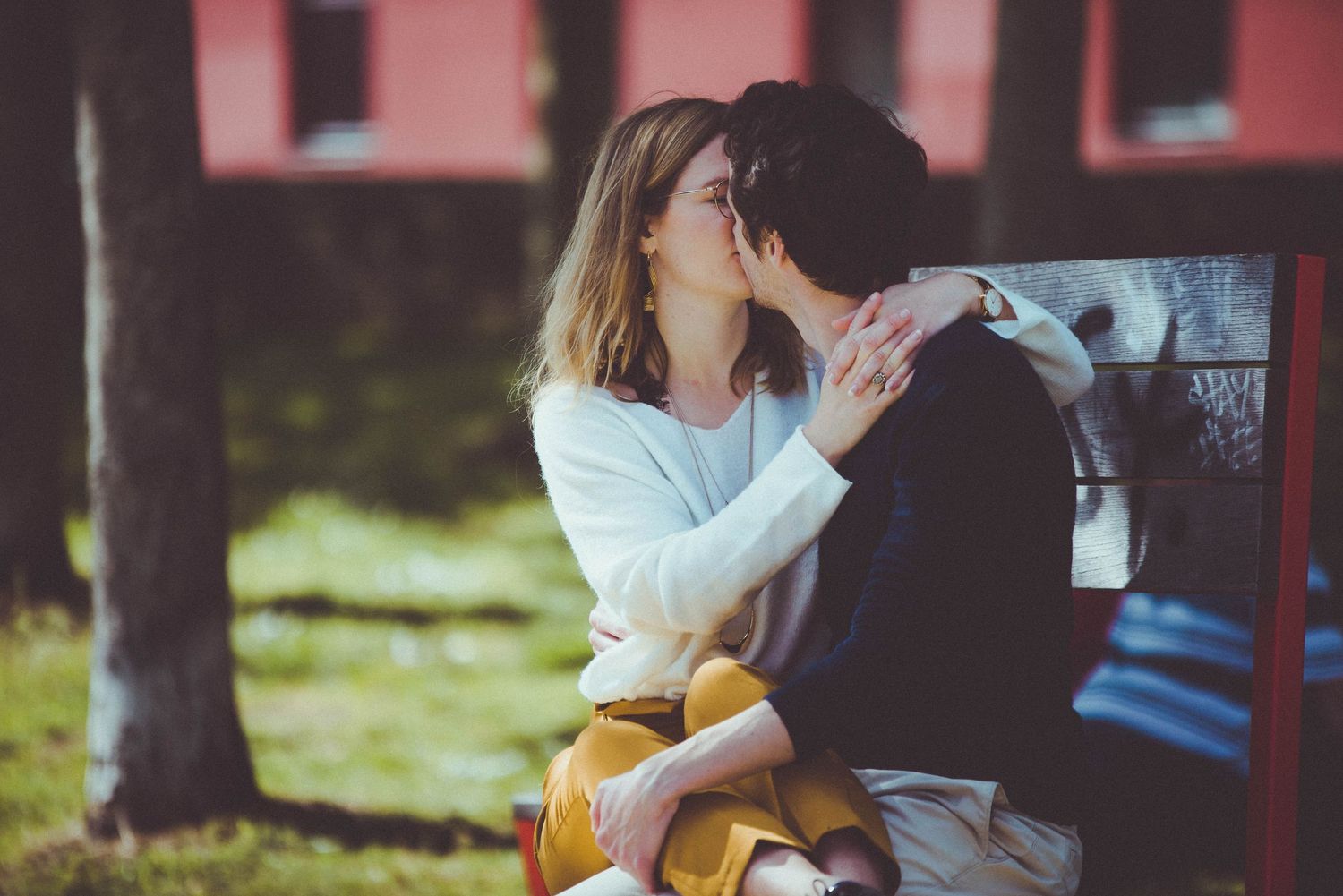 Couple échangeant un baiser tendre en extérieur lors d’une séance engagement en Bretagne, ambiance lumineuse et naturelle.
