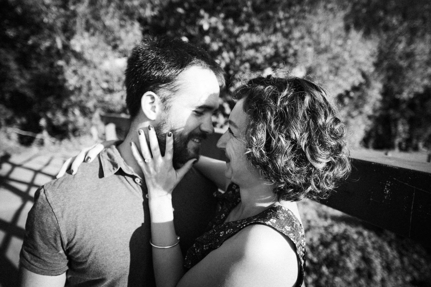 Moment complice en noir et blanc entre un couple amoureux en extérieur.