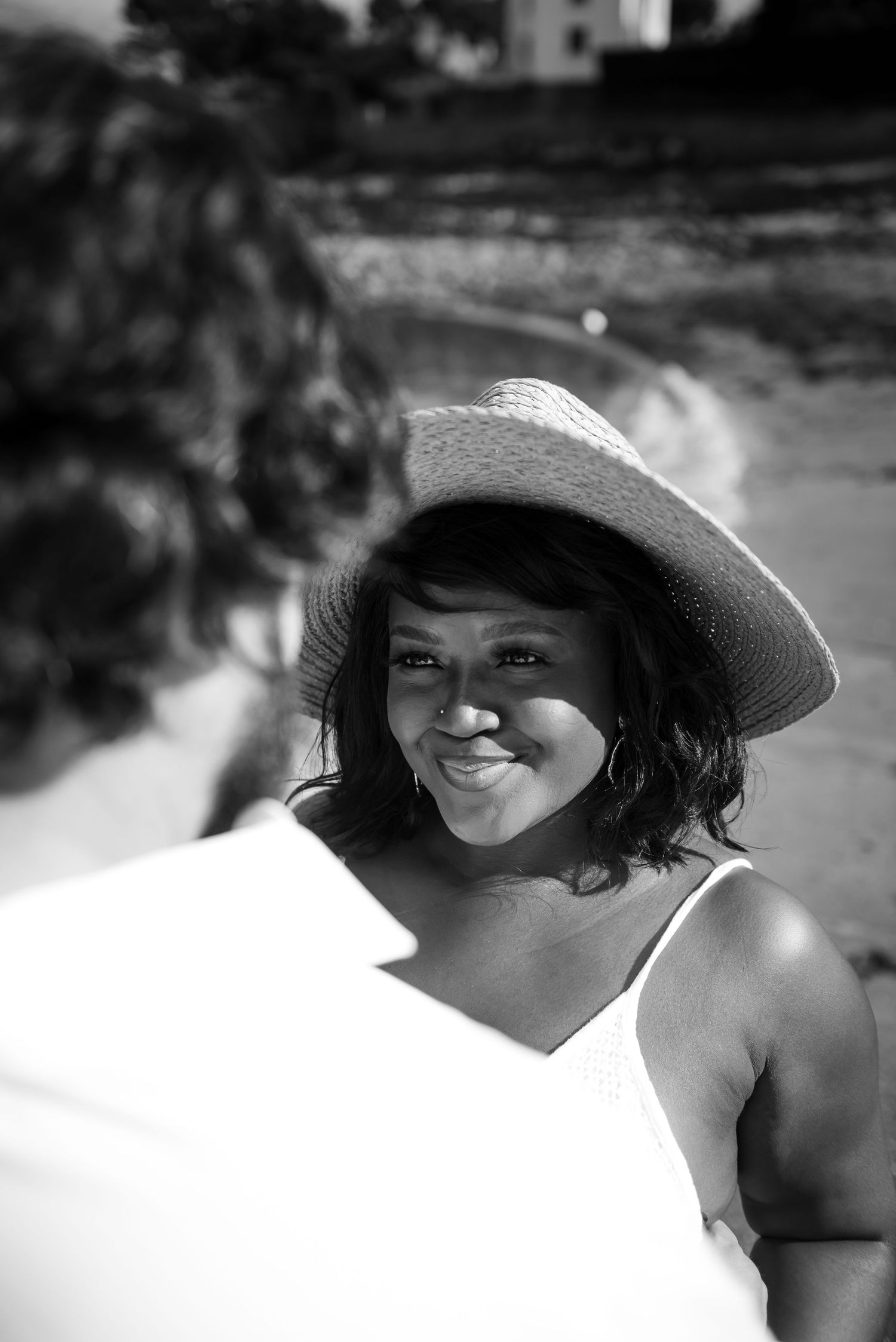 Portrait naturel en noir et blanc d’une femme souriante sur une plage en Bretagne lors d’une séance engagement en bord de mer.