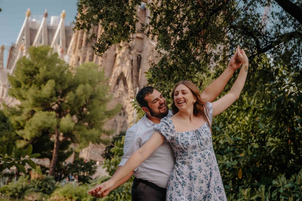 Intimate portrait of couple leaning against Gaudí architecture.