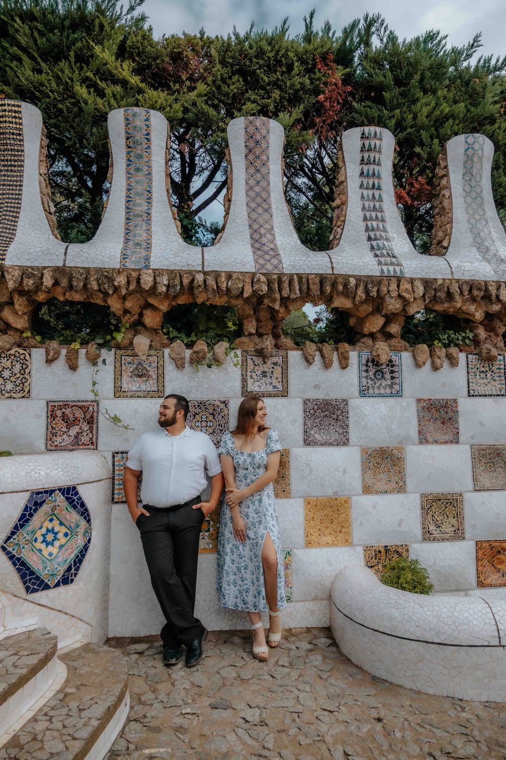 Elena and Michael holding hands in front of Sagrada Familia on a sunny morning.