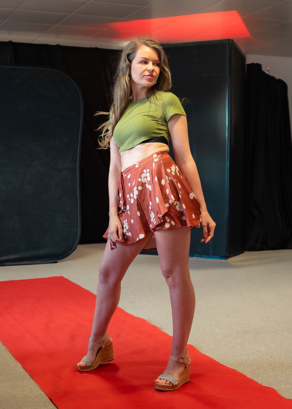 A dancer performs a dynamic sequence of movement poses on a red carpet in a studio space.