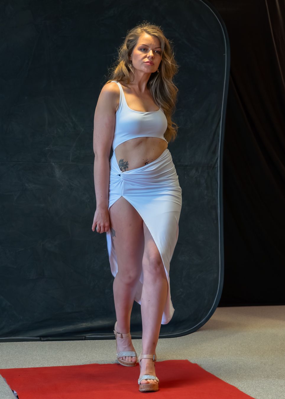 A person in a white top and shorts poses in a dynamic sequence against a dark studio backdrop.