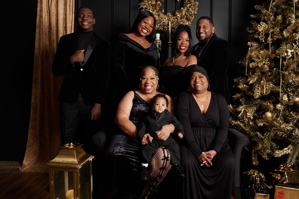 Holiday family portrait with decorated Christmas tree and gold backdrop.