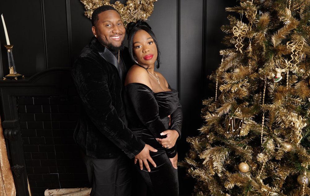 Elegant couple's portrait by decorated Christmas tree with gold ornaments.