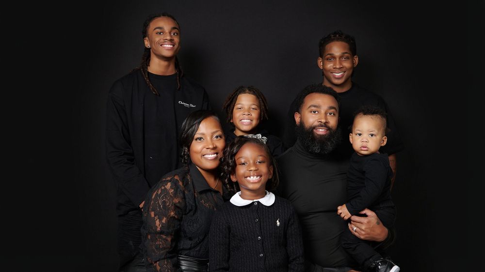 Elegant family portrait with everyone dressed in black against a dark background.