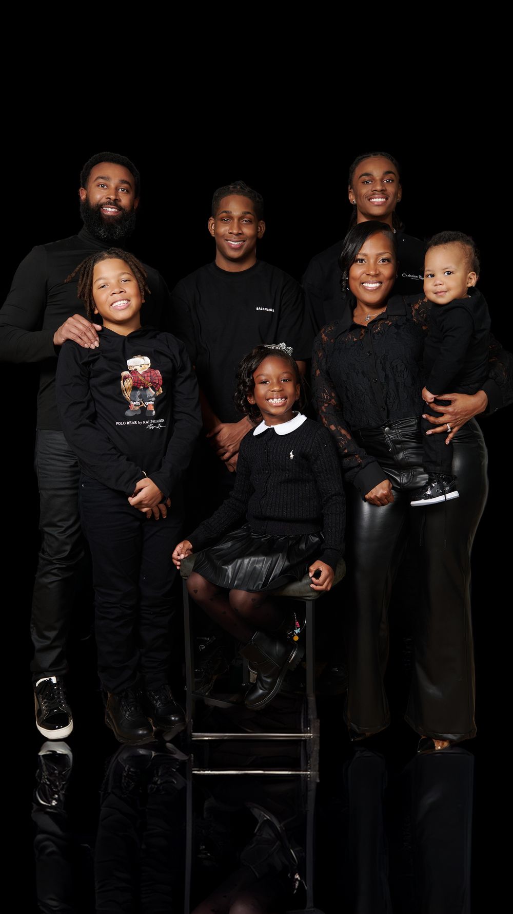 Modern family photo with seven people dressed in black against dark background.