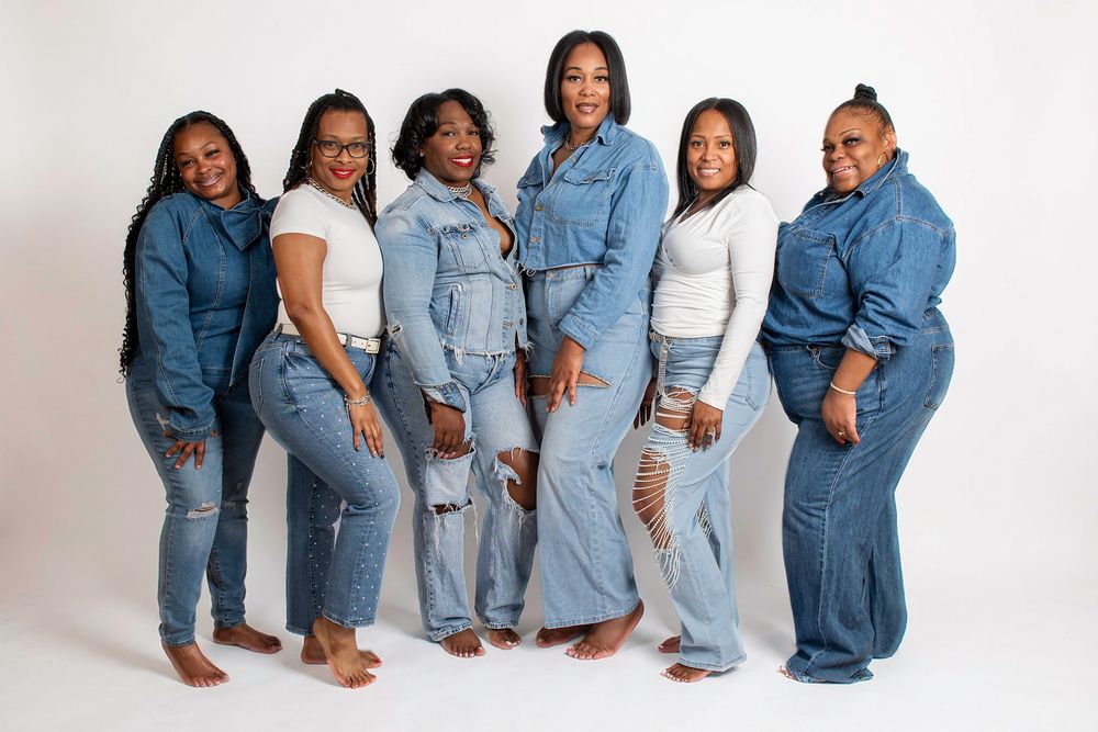 Group photo of people wearing coordinated denim outfits in a white studio setting.