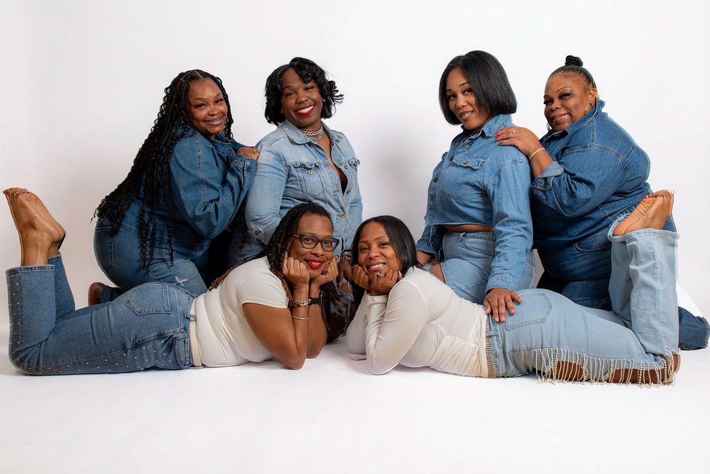 Family group lying down in casual denim outfits for a relaxed studio photoshoot.