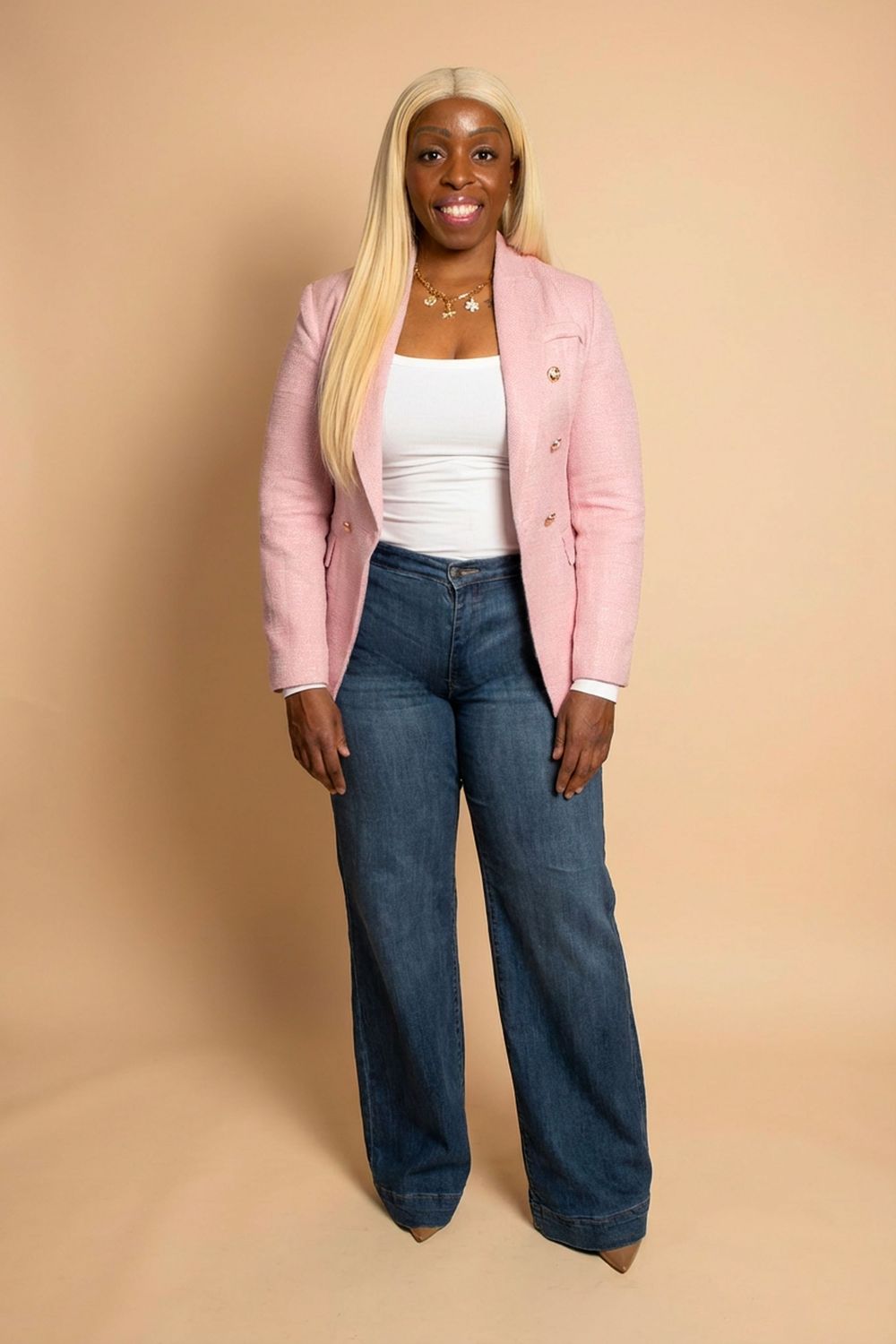 Stylish outfit featuring a pink blazer, white top and wide-leg jeans against a neutral background.