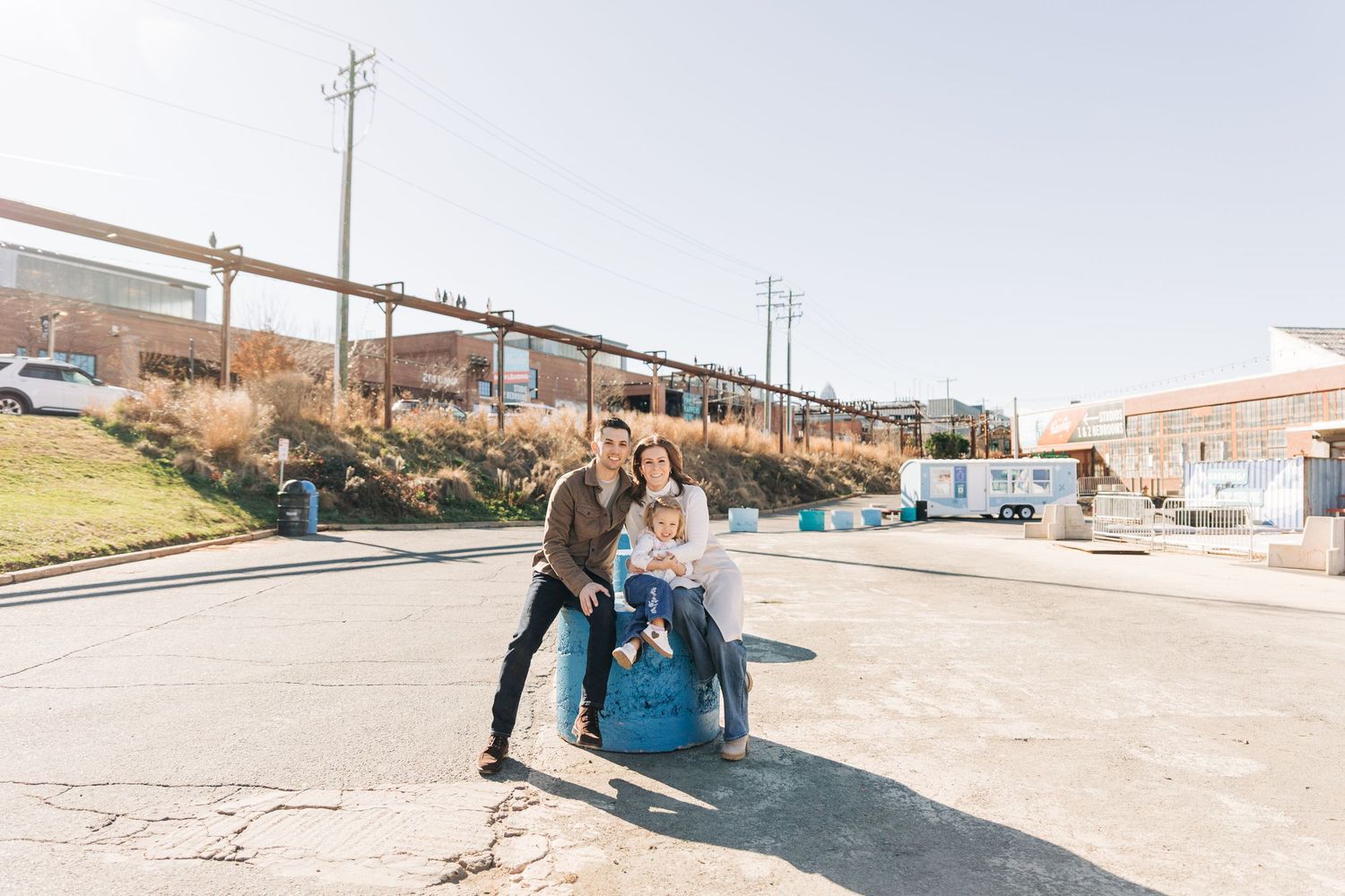 A family sits in Camp North End with the city behind them for family photo session.
