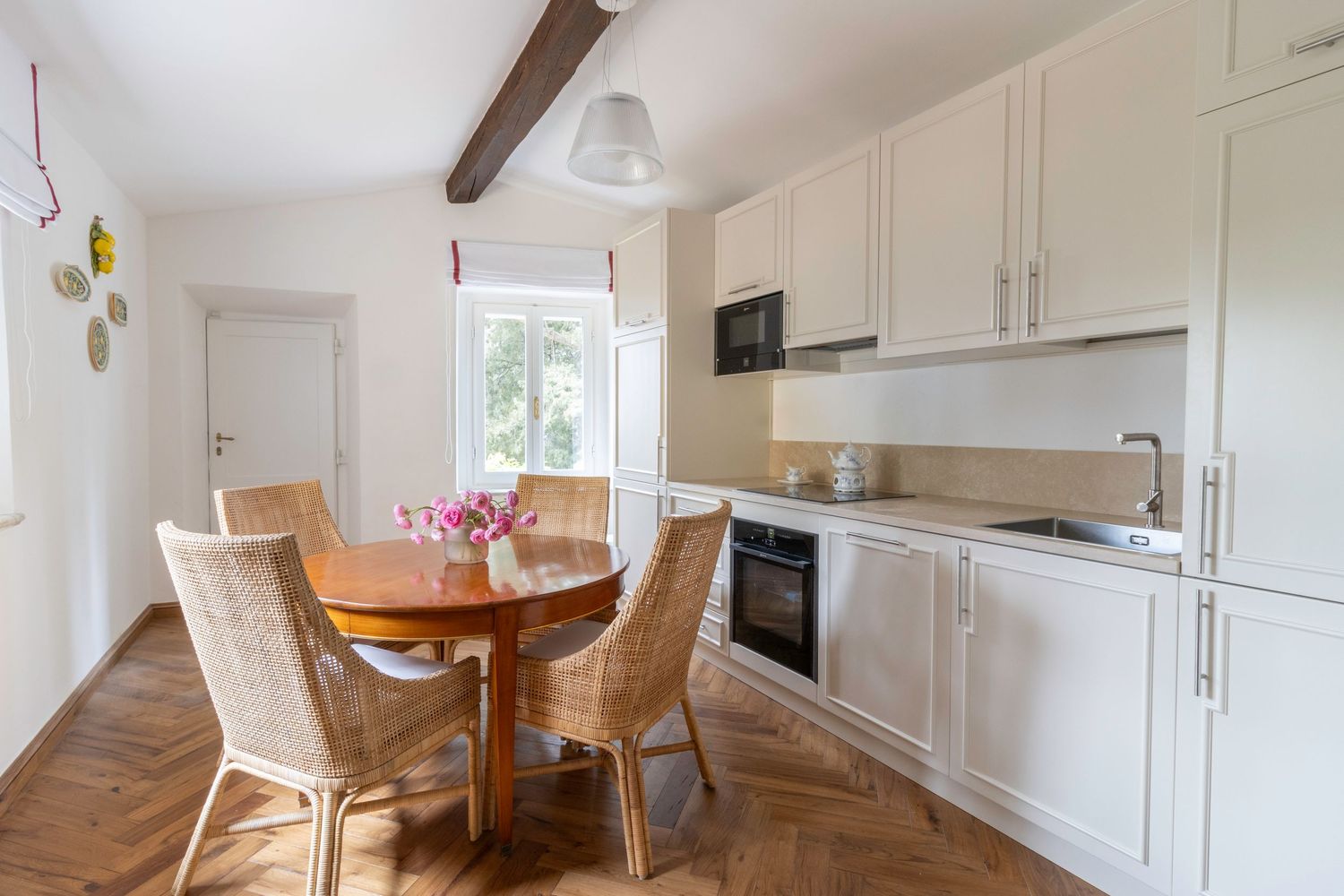 Professional real estate photographer in Tuscany, Italy. Bright modern kitchen with white cabinets and wooden beams.