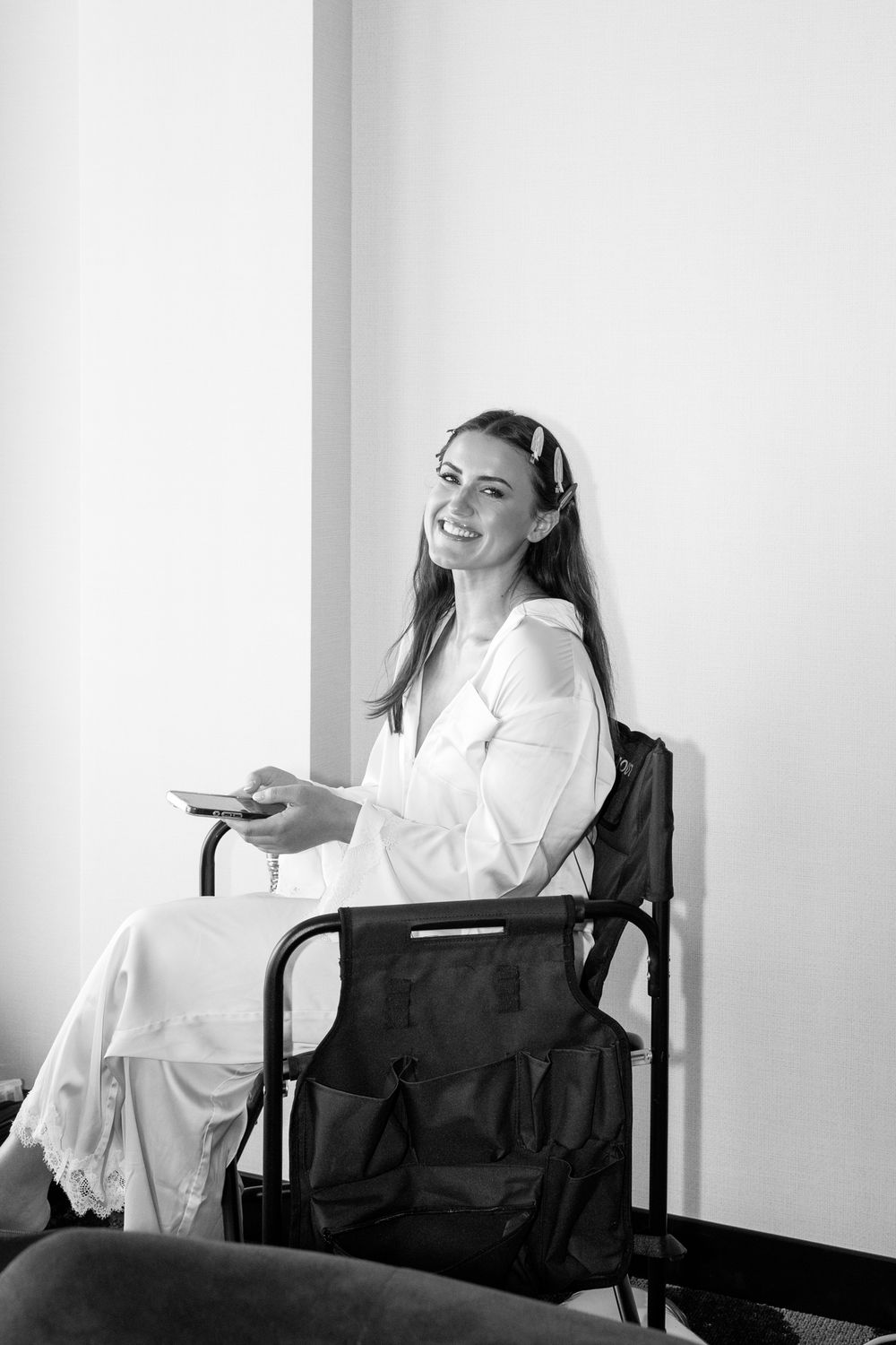 A black and white portrait of someone getting ready in a white robe and veil.