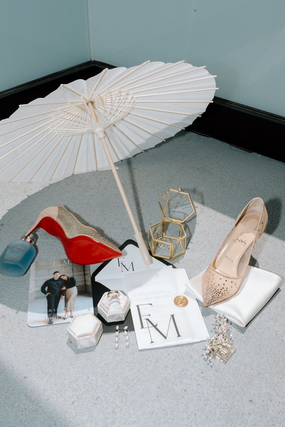 Collection of wedding accessories including white paper parasols, high heel shoes, and geometric decor on a light gray floor.