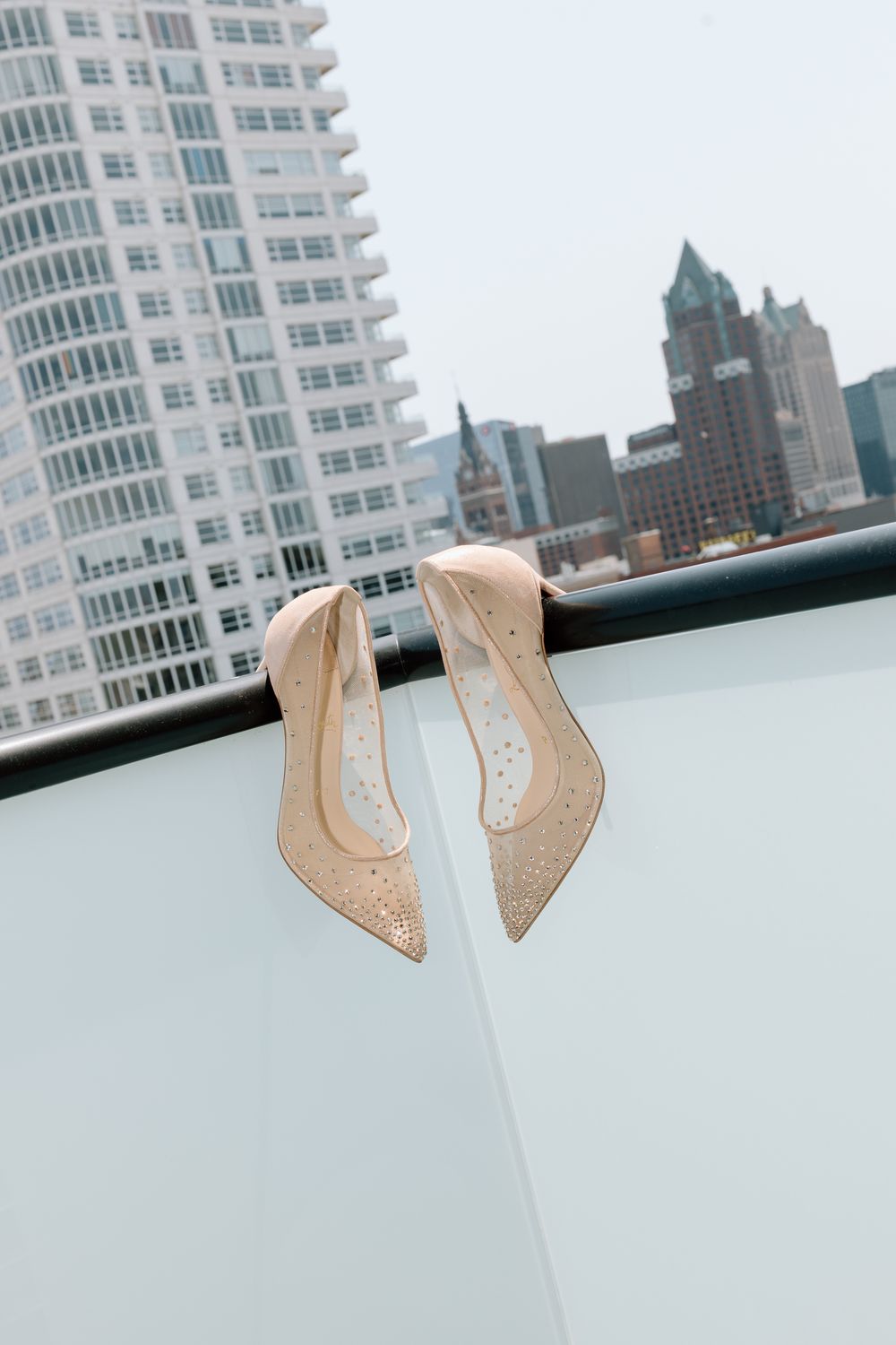 Nude sparkly wedding heels photographed against a city skyline backdrop.