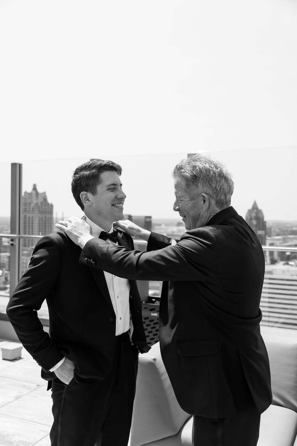 Black and white sequence of playful moments between two people in formal attire on a rooftop.