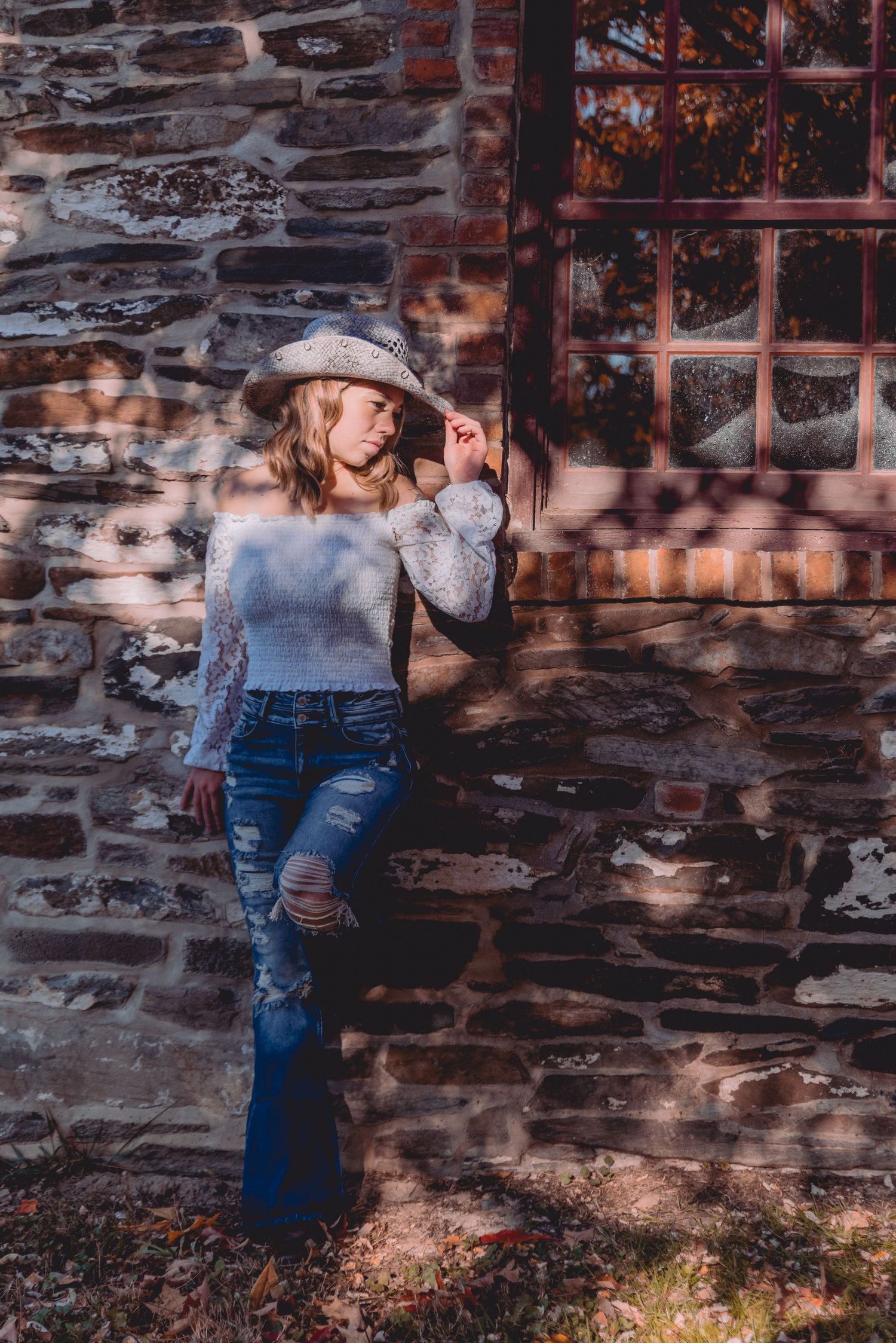 Artistic portrait series against rustic brick wall shows romantic couple in casual denim outfits in natural lighting.