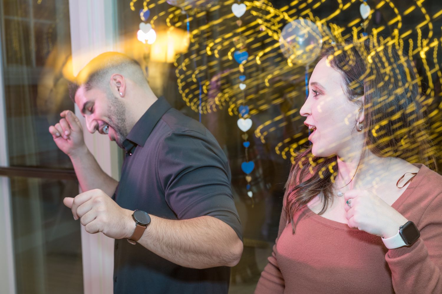 A group of people dancing and celebrating at a party with golden bokeh lights in the background.