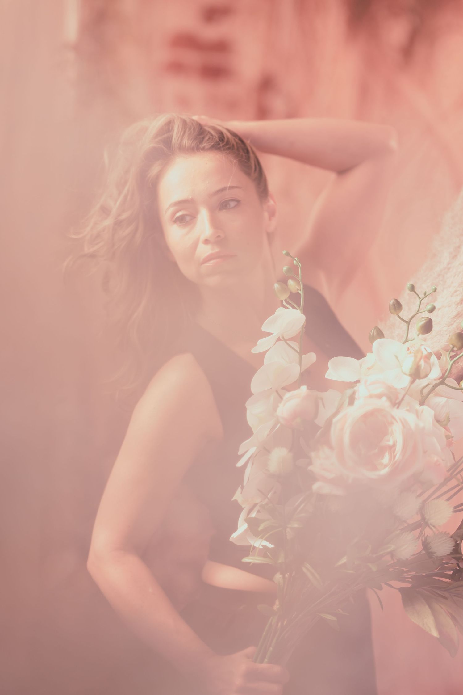 Dreamy pink-tinted portrait with delicate white flowers creating an ethereal romantic mood.