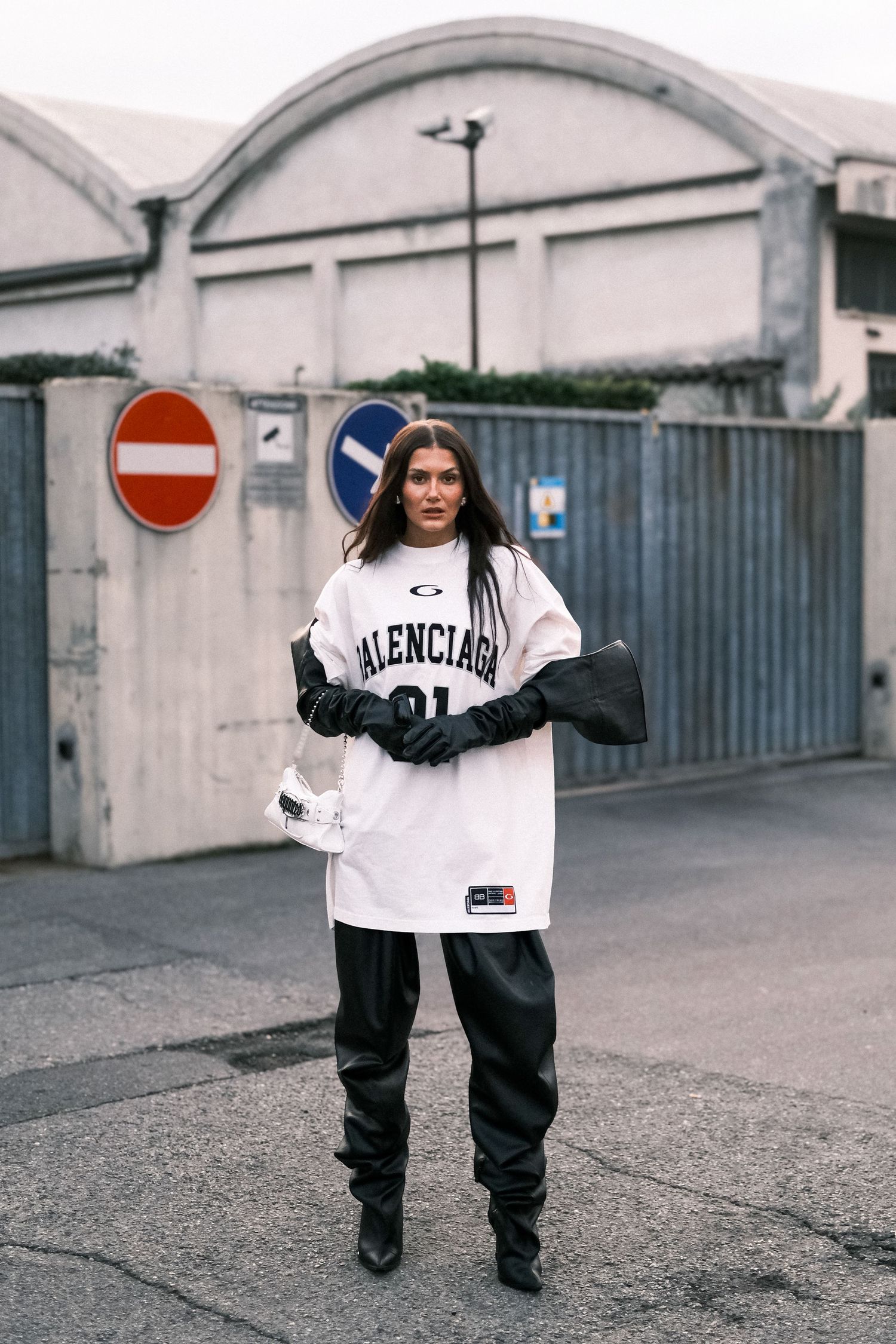 Person wearing an oversized white Balenciaga sweatshirt and baggy black pants poses in an urban setting.