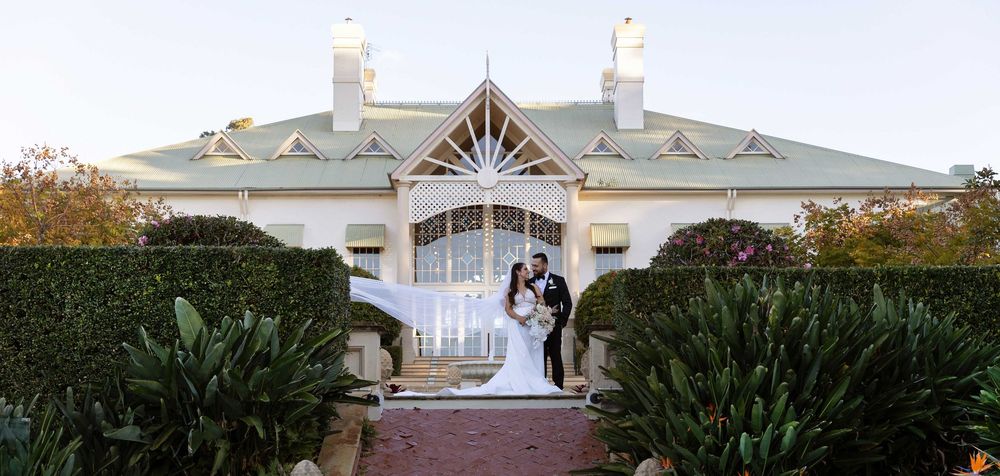 Bride and groom stand together outside a stunning heritage mansion wedding venue at dusk.