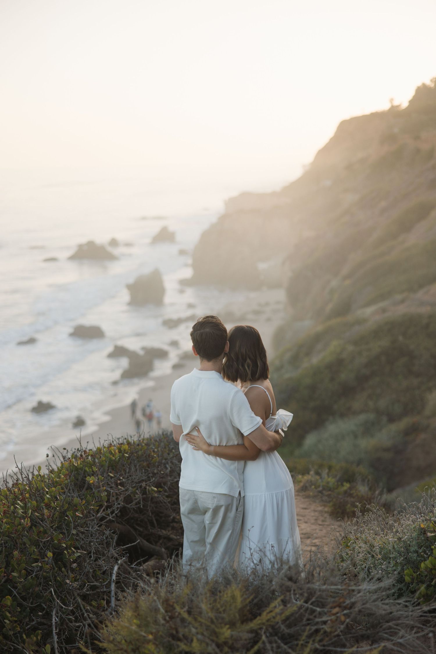 Engagement session at El Matador Beach in Malibu with a couple embracing on a cliff overlooking the ocean