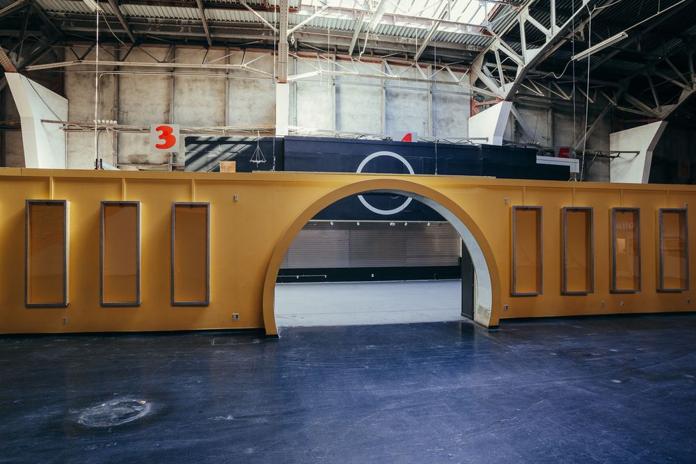 Wide angle view of an empty commercial space with high ceilings and yellow accent walls.